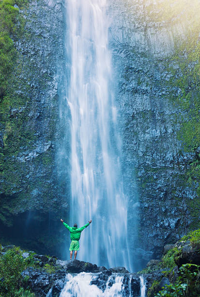 istock Man standing at base of massive waterfall 506132619