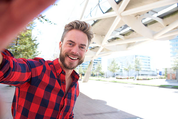 Smiling man taking selfie Smiling man taking selfie outside in the city man beard plaid shirt stock pictures, royalty-free photos & images