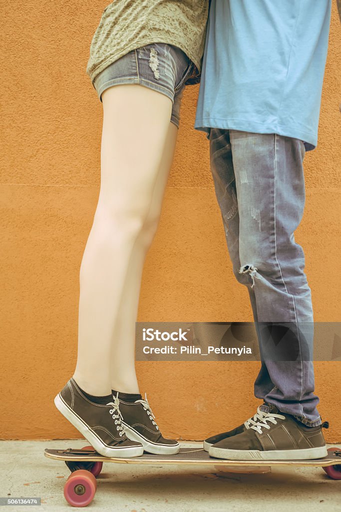 Closeup kissing couple at skateboard and red wall background Closeup kissing couple at skateboard and red wall background. Valentine's Day, 14th February celebration, Valentine. Love concept. Adult Stock Photo