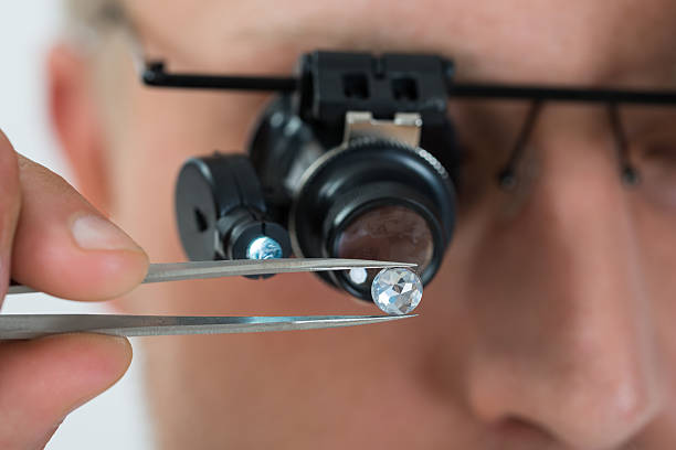 Person Looking At Diamond With Magnifying Loupe Close-up Of Person Looking At Diamond With Magnifying Loupe diamond gemstone stock pictures, royalty-free photos & images