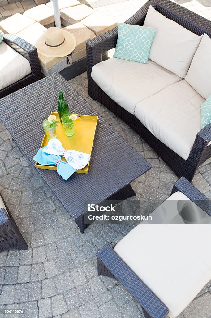 Upmarket outdoor patio with garden furniture View from above of a vacant upmarket outdoor patio with modern garden furniture with comfortable upholstered cushions on paving with a central table with a tray of chilled drinks Architecture Stock Photo
