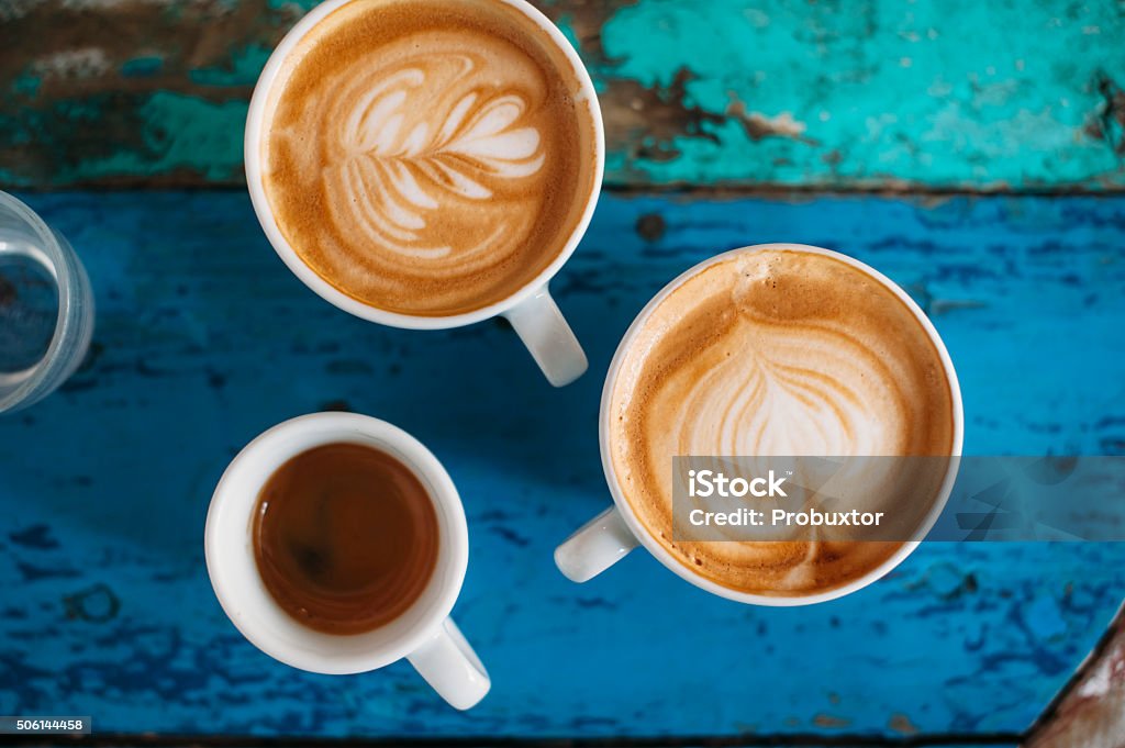 fresh tasty coffee cups two fresh tasty cappuccino coffee cups with latte art on it and one espresso cup on the coffee table Coffee - Drink Stock Photo