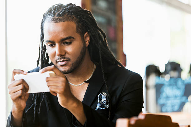 istock Young black man in coffee shop with smartphone 506145938