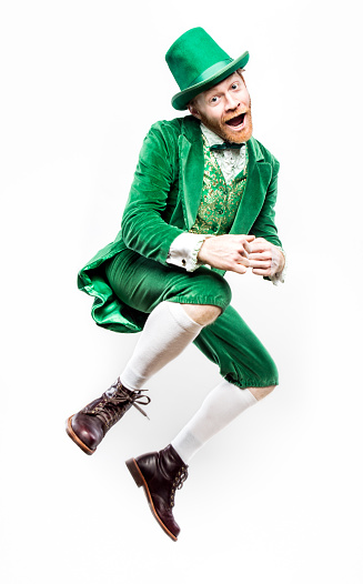 A portrait of a stereotypical Irish character doing a dance to celebrate Saint Patricks day.  He smiles, jumping into the air with both feet off the ground.  Isolated on white studio background.