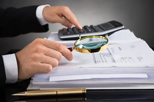 Photo of Businessperson Checking Invoice With Magnifying Glass