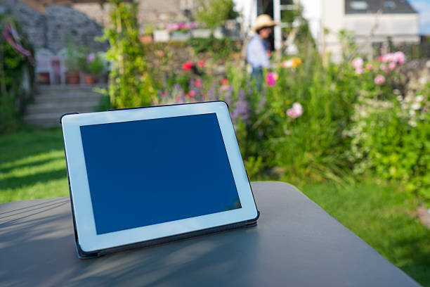 istock Tablet pc on a table with woman in her garden 506153283
