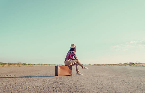 Traveler sits on vintage suitcase stock photo