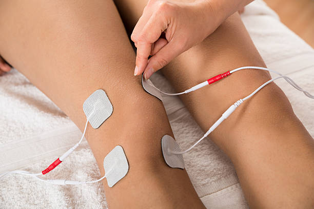 Close-up Of Therapist Placing Electrodes On Woman's Knee