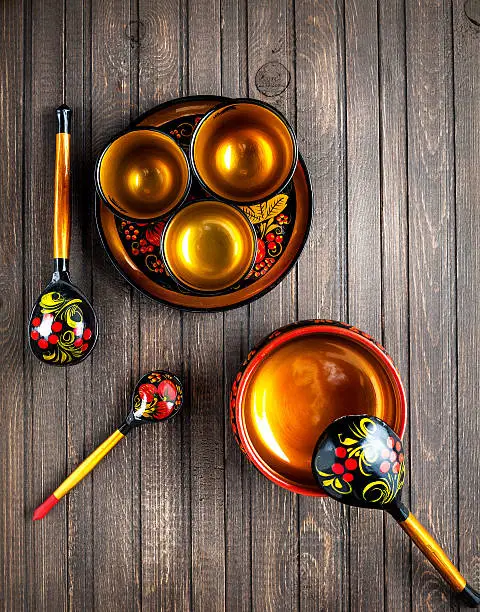 Wooden dishes, painted with floral ornament in the style of Khokhloma Russian wood art on the table