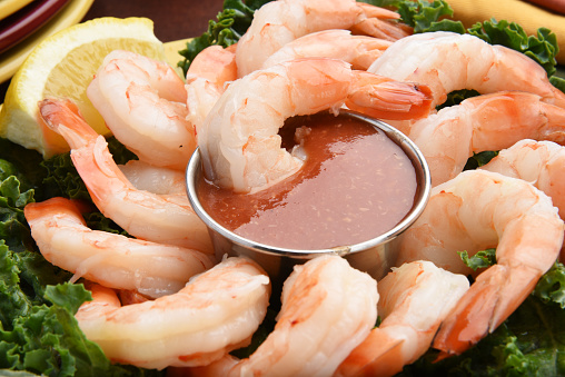 Closeup of shrimp cocktail with lemon wedges and garnish
