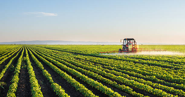 tractor en el campo de soja pulverización - tierra cultivada fotografías e imágenes de stock