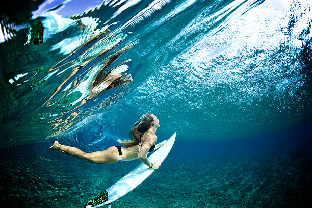 istock Surfer girl duckdives a wave with reflection 506165134