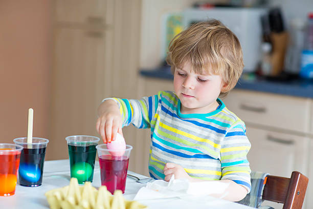 istock Little kid boy coloring eggs for Easter holiday 506166778