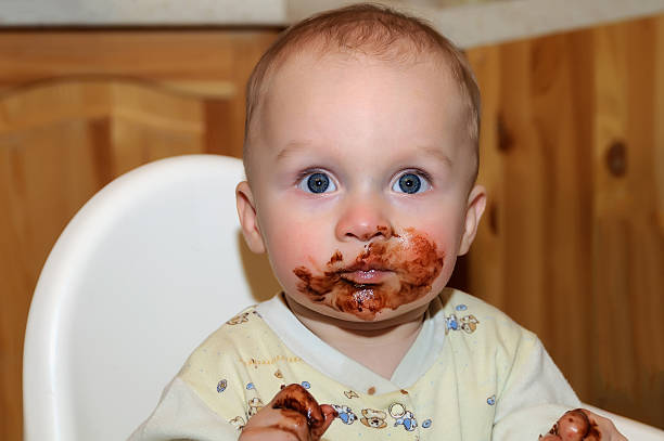 child boy grimy chocolate Portrait of a child in the highchair. His face and hands smeared with chocolate eating chocolate messy men stock pictures, royalty-free photos & images