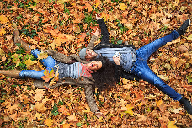 Smiling couple lying down on leaves carpet