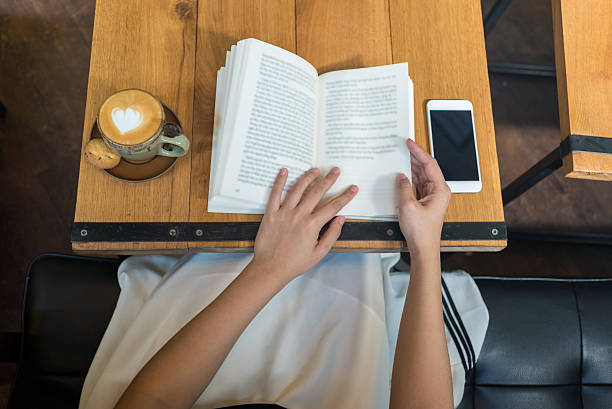Nice frothed milk cappuccino with book and smartphone on table stock photo