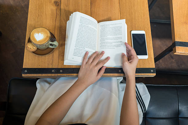 nice frothed leite cappuccino com livro e smartphone na mesa - drinking tea cup drink - fotografias e filmes do acervo