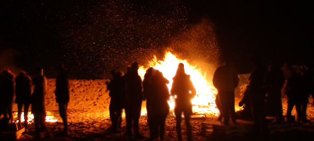 View Of Group Of People Standing By Burning Campfire