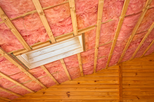 Fiberglass insulation installed in the sloping ceiling of a timber house.