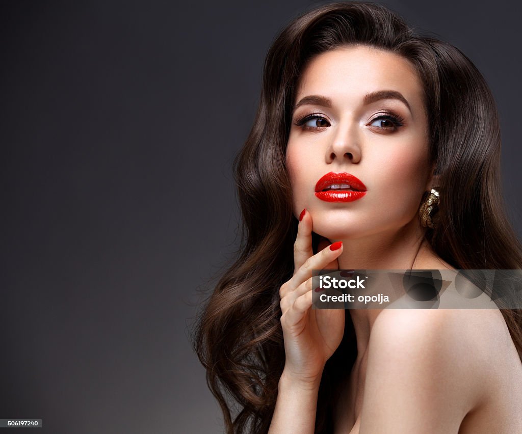 Beauty Model Woman with Long Brown Wavy Hair.  Red Lips Beauty Model Woman with Long Brown Wavy Hair. Healthy Hair and Beautiful Professional Makeup. Red Lips and Smoky Eyes Make up. Women Stock Photo