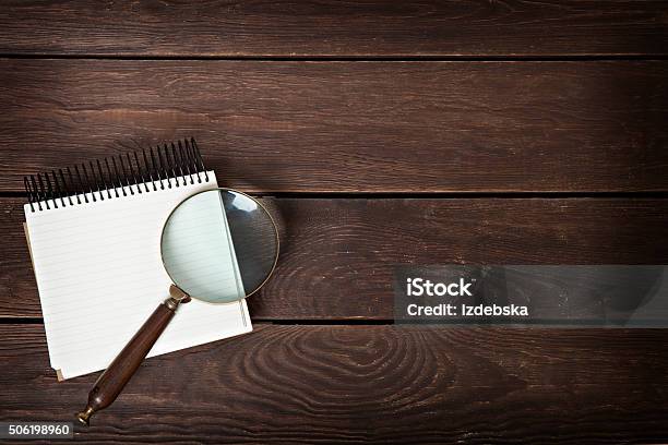 Notebook With A Magnifying Glass On A Wooden Background Stock Photo - Download Image Now