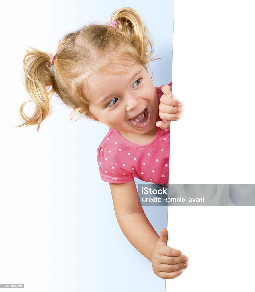 Smiling little girl looking behind a white board blonde girl emerges from a billboard Child Stock Photo