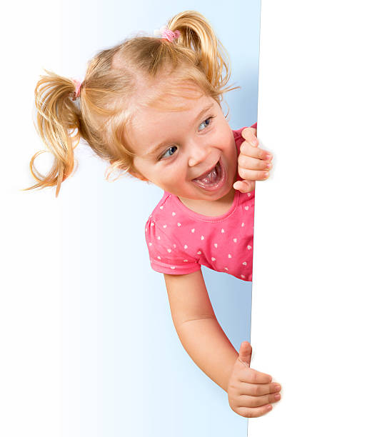 sorridente menina olhando por trás de um quadro branco - peeking imagens e fotografias de stock