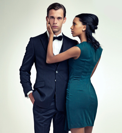 A portrait of a handsome young man in a vintage suit standing with a gorgeous young woman on his arm