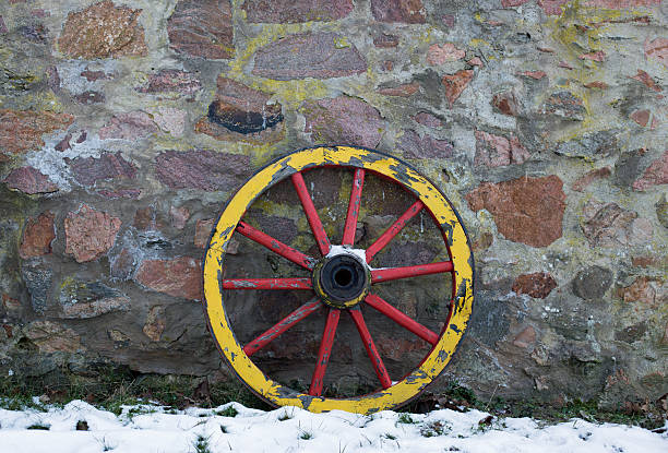 Old wooden wagon wheel on a stone wall in winter