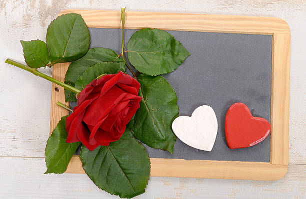 istock red rose and black slate on a wood background 506217764