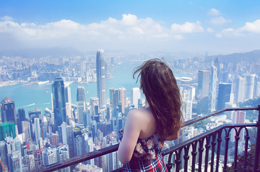 Hong Kong, Hong Kong S.A.R. - November 22, 2015: Girl look at Hong Kong buildings panorama from Victoria Peak park on sunny day in Hong Kong.