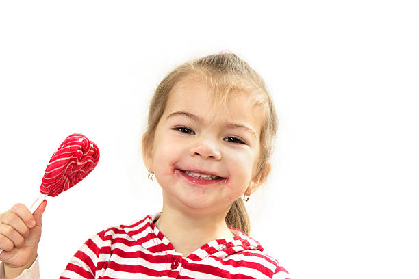 陽気な女の子に棒付きキャンディ - child valentines day candy eating ストックフォトと画像
