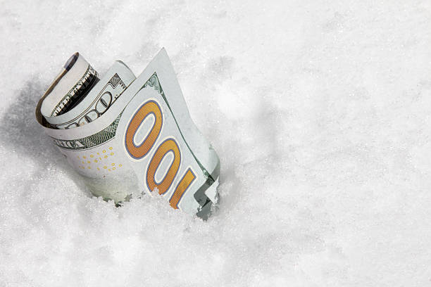 сто доллар билл частично зарываются в снегу - frozen currency finance ice стоковые фото и изображения