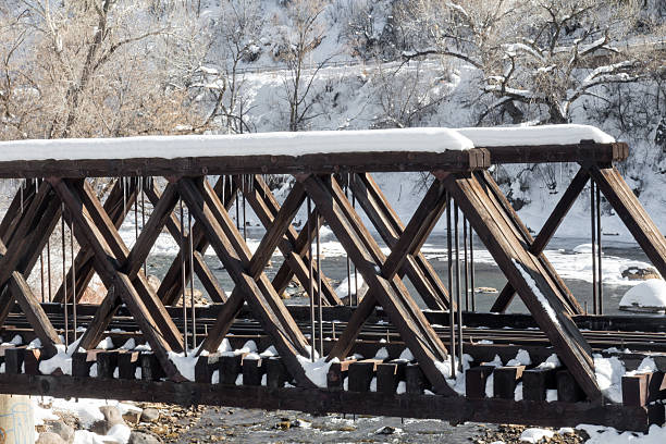 Wooden train bridge crossing the wintertime Animas river Image of a wooden trestle bridge crossing the Animas river in Durango, Colorado.  The wood bridge is for the narrow gauge railroad that is a local tourist attraction.  The river is surrounded by snow and ice. tressle stock pictures, royalty-free photos & images