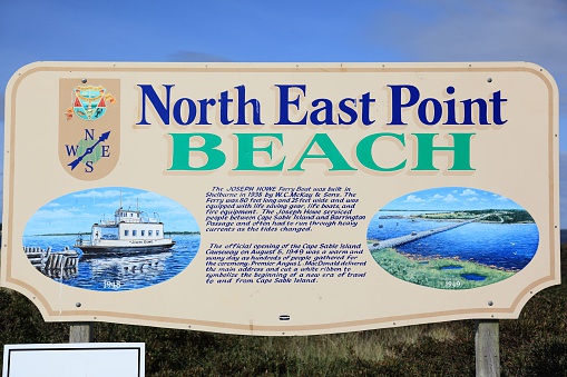 Cape Sable Island, Canada - September 20, 2014: North East Point beach sign, located in Cape Sable Island, Nova Scotia, Canada.  Sign shows that  access to Cape Sable was by ferry in the pass and it shows the present causeway going to Cape Sable Island as it is now.  Two pictures in the sign show this with the corresponding wrtting.