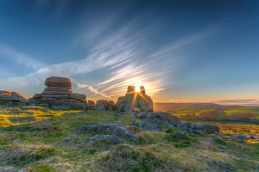 Hound Tor at sunset with the sun shining between the rocks on Dartmoor in Devon