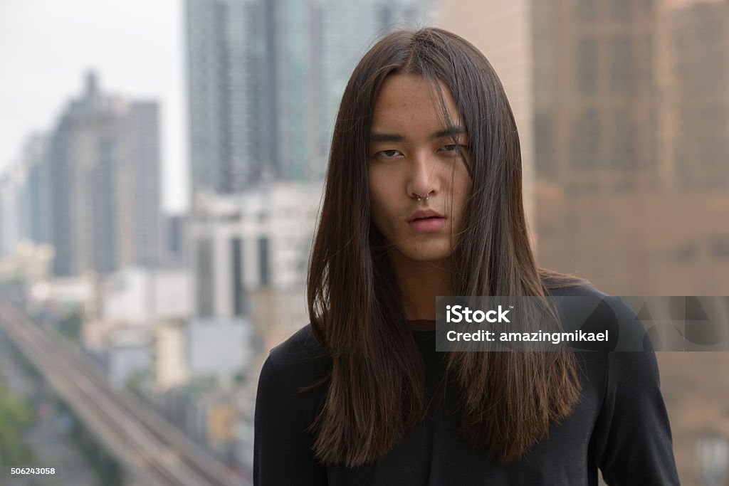 Asian man with long hair outdoors Handsome slim Asian man with long hairstyle outdoors 18-19 Years Stock Photo