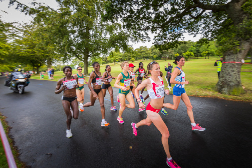 Glasgow, UK - July 27, 2014: Female athletes run through Bellahouston Park in Glasgow cheered on by locals during the 2014 Commonwealth Games marathon race.