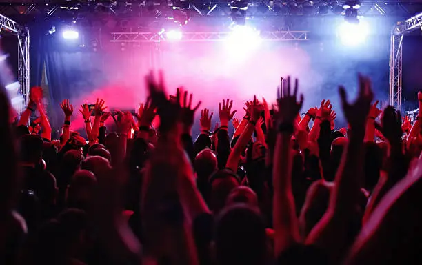 silhouettes of people on a rock concert raising hands