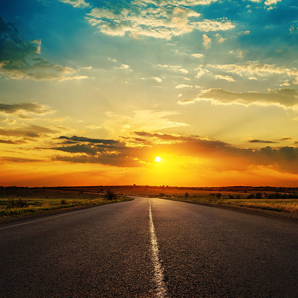 istock orange sunset in clouds over asphalt road 506247126