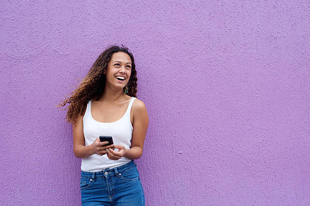 istock Smiling young woman with mobile phone looking away 506248238
