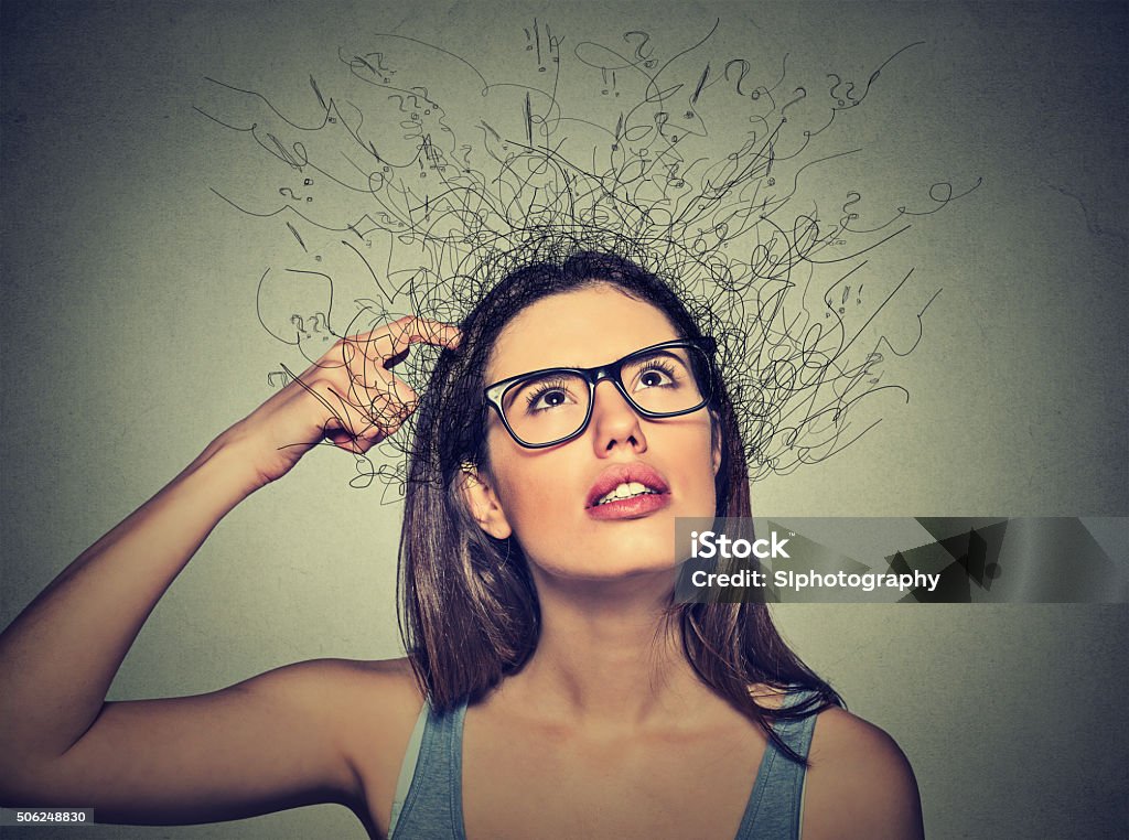 woman scratching head, thinking brain melting into lines Closeup portrait young woman scratching head, thinking daydreaming with brain melting into lines question marks looking up isolated on gray background. Human facial expressions, emotion feeling sign Attention Deficit Hyperactivity Disorder Stock Photo