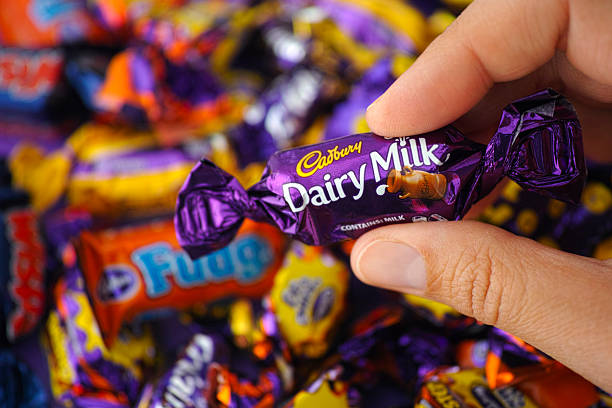 Cadbury Dairy Milk candy in womans hand Paphos, Cyprus - November 27, 2015: Cadbury Dairy Milk candy in womans hand with background of Cadbury candies. cadbury plc photos stock pictures, royalty-free photos & images