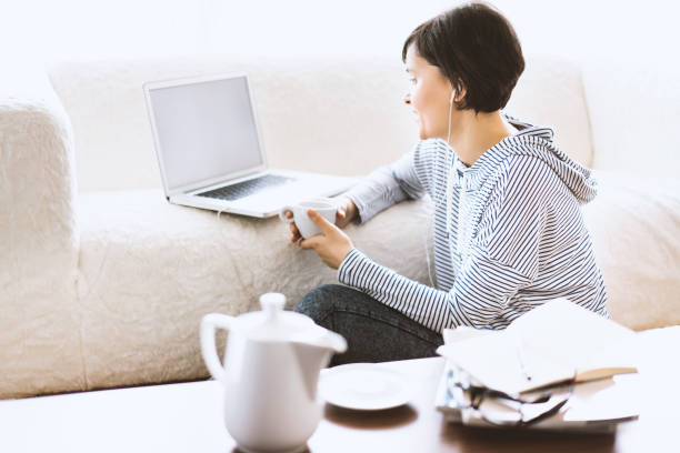 istock Young woman sitting on the floor using laptop 506252520