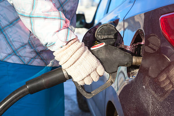 istock Female hand in mittens refueling car at winter 506283319