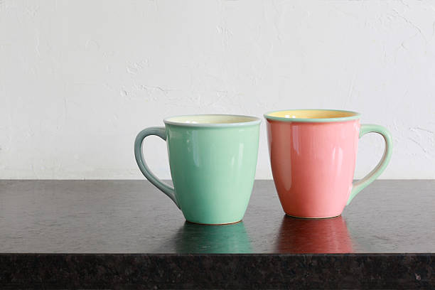 Two pastel mugs on black granite kitchen countertop