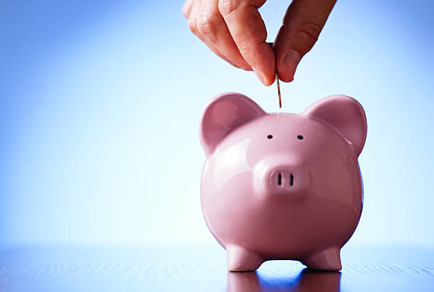 istock Man placing a coin into a piggy bank 506286057