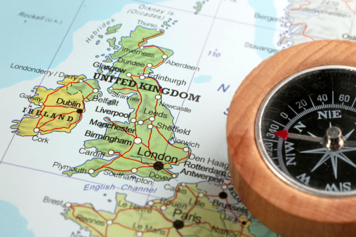 Compass on a map pointing at United Kingdom and Ireland, planning a travel destination