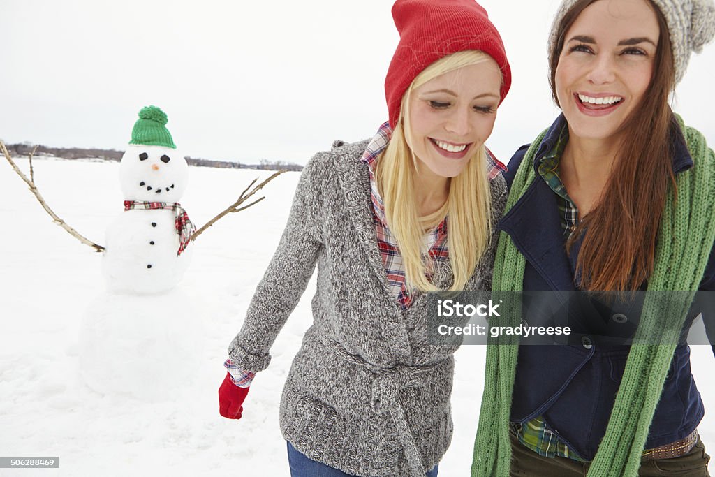 Heading home after making a snowman Cropped shot of two young women walking passed a snowman 30-39 Years Stock Photo