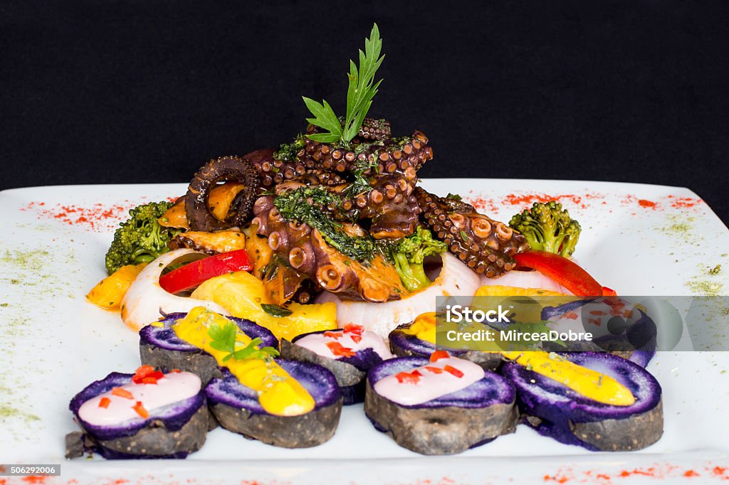 Grilled Octopus, gourmet dish from Peru. Served with purple potatoes Grilled Octopus, gourmet dish from Peru. Served with purple potatoes (nativa), huancaina sauce, rice, onion,  vegetables. Arequipa Region Stock Photo